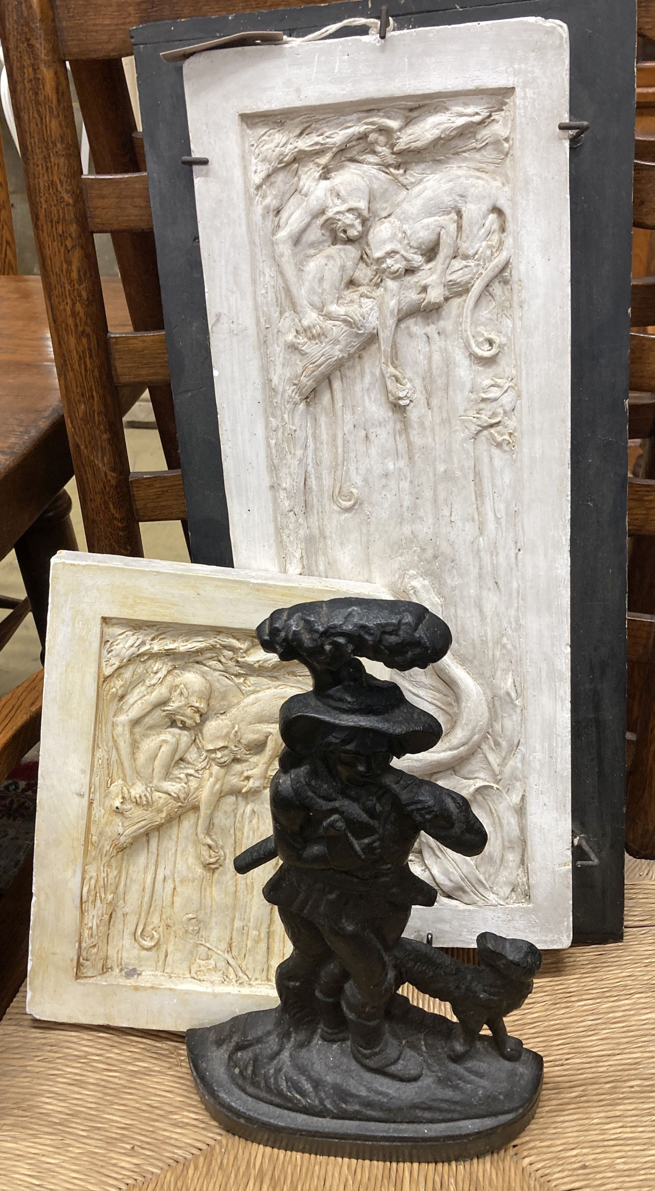 A pair of rectangular cast plaster plaques, larger 59cm high, 22cm wide together with a Victorian style cast iron doorstop